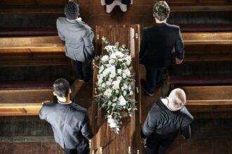 Cérémonie funéraire avec des proches portant un cercueil en extérieur